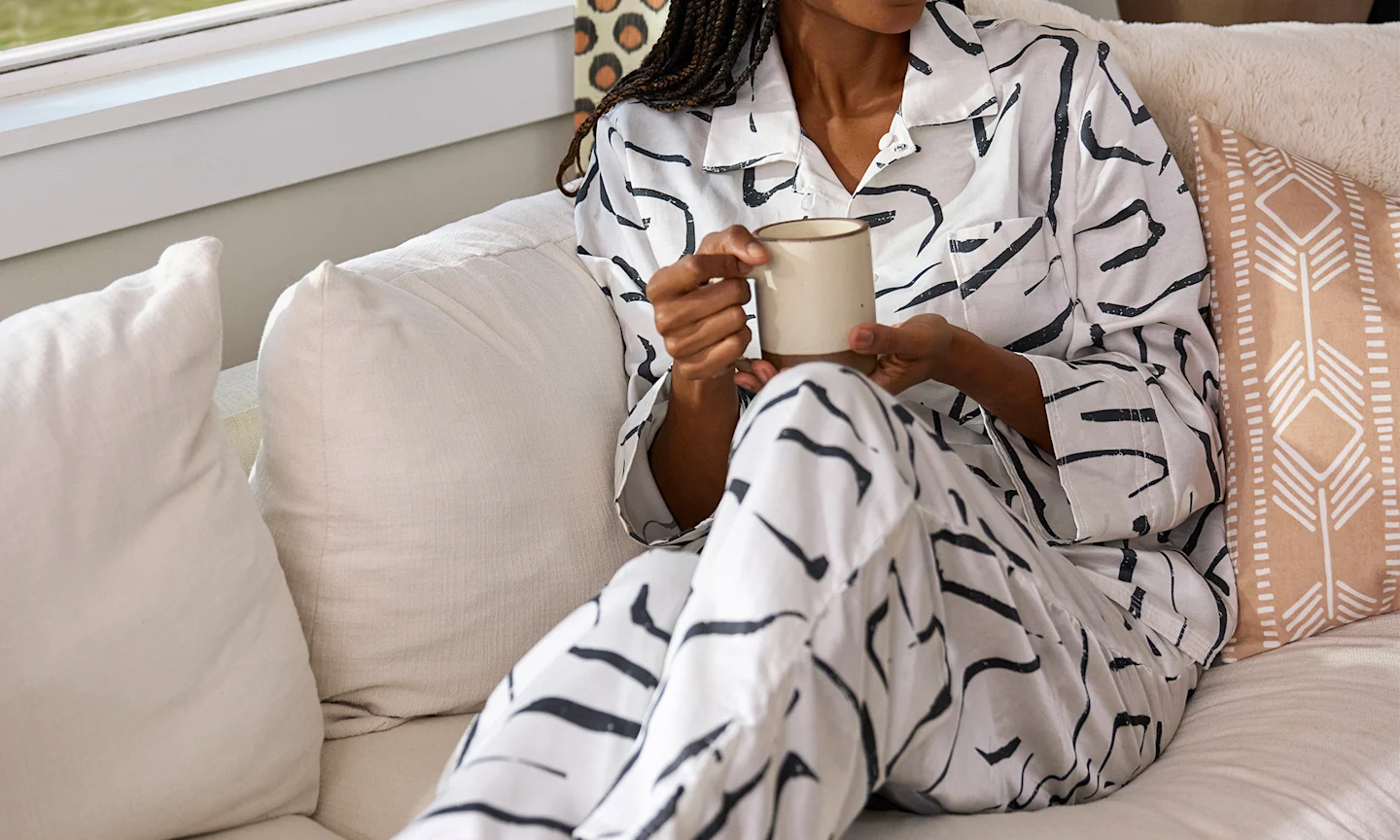 Woman on a couch in black and white cotton silk pajamas.