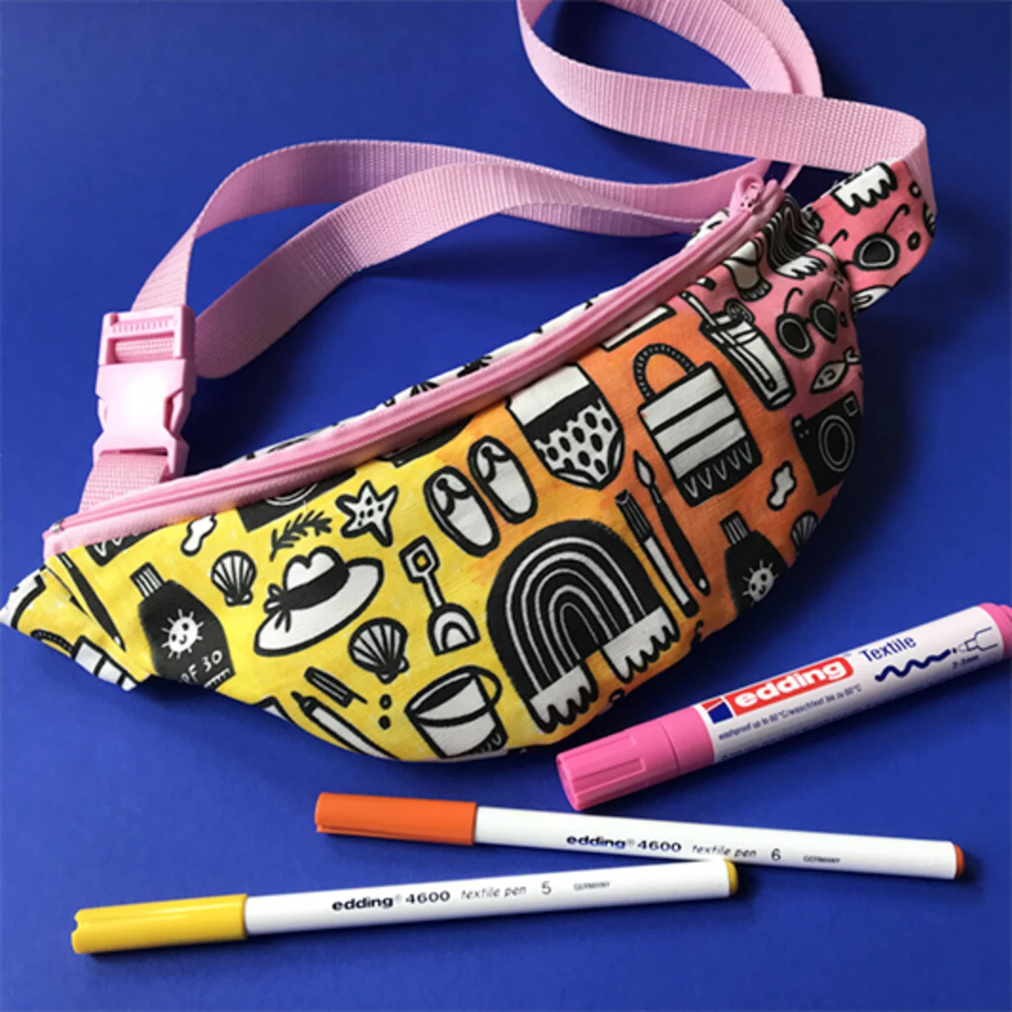 Fanny pack and fabric markers on blue background