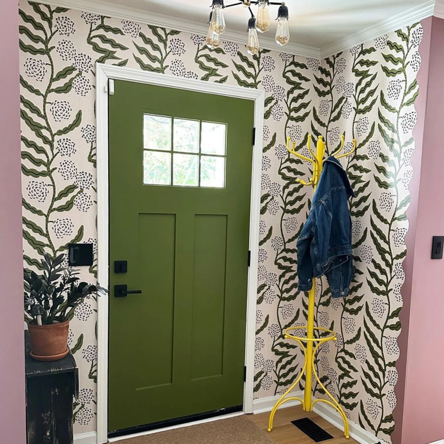 Entryway with green door and green vining wallpaper.