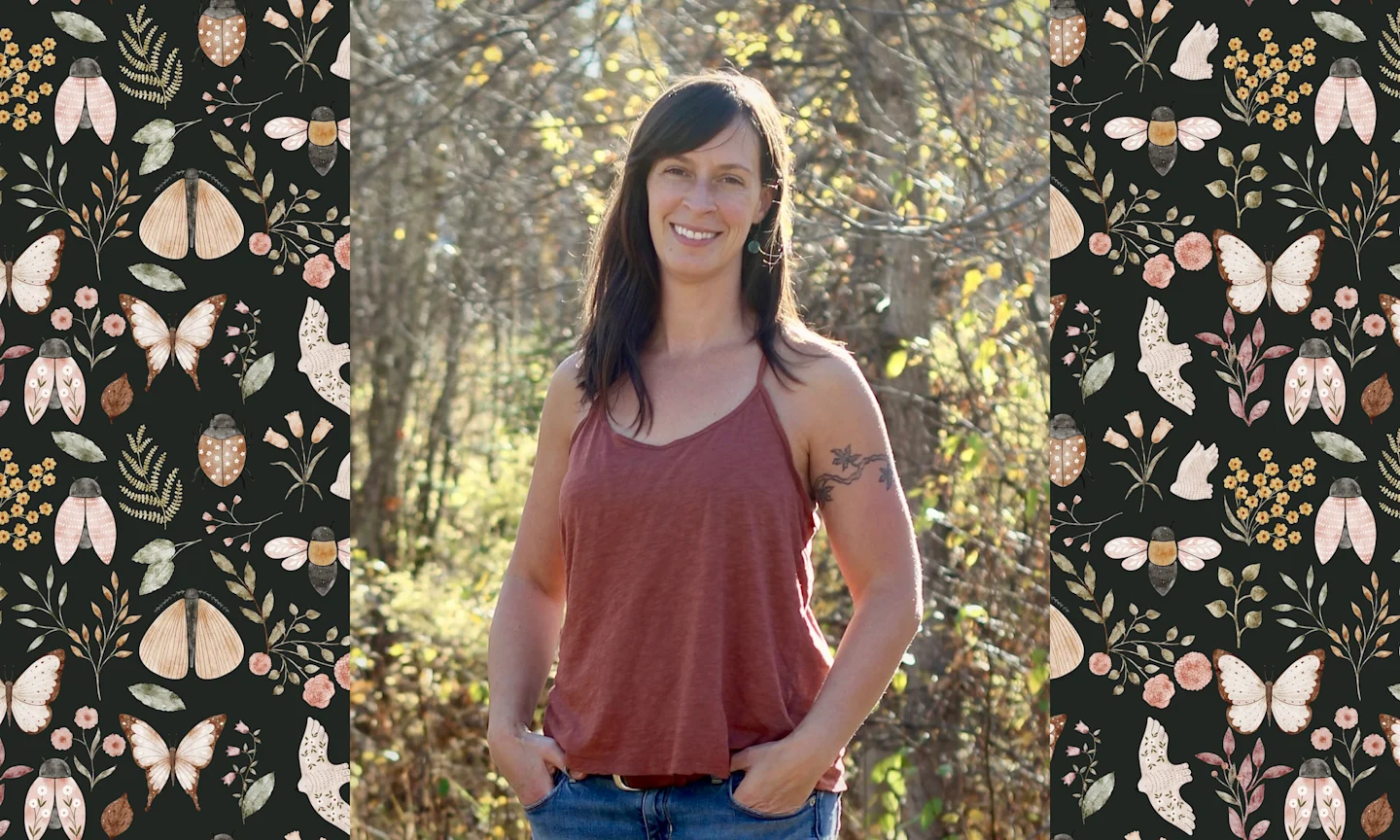 a woman in a tank top, standing in front of a tree in a forest