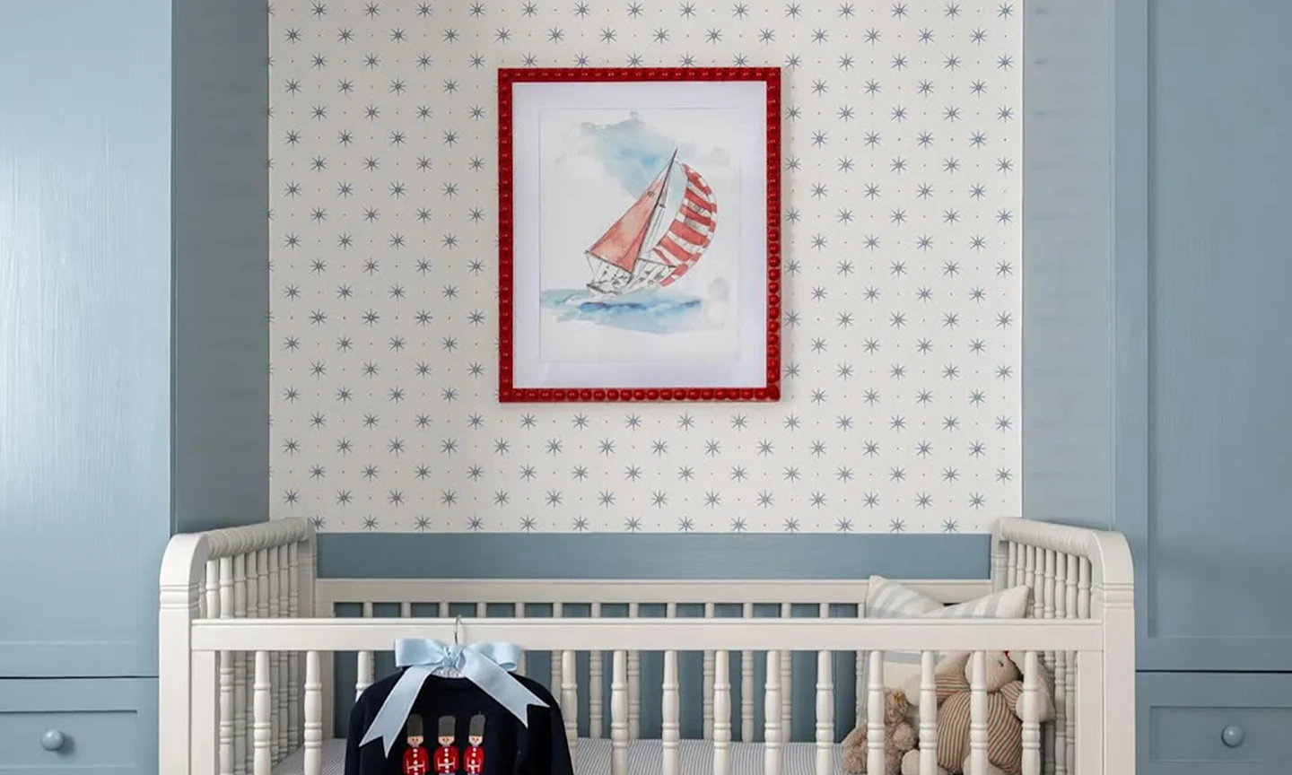 Nursery with star wallpaper and a art print with a sailboat.
