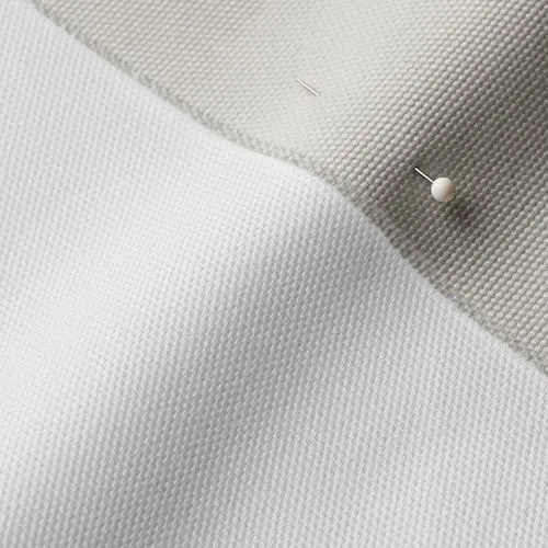 A close-up photo of white fabric with a pin running through it